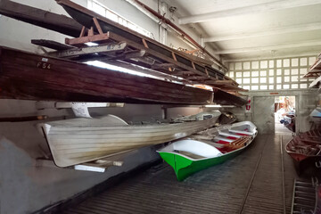 Interior of a hangar or boathouse of a rowing club or boatyard with boats on racks and on the floor