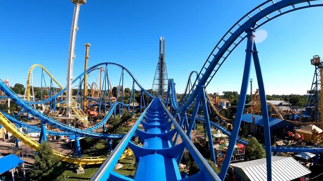 A first-person perspective of a blue roller coaster track at an amusement park.
