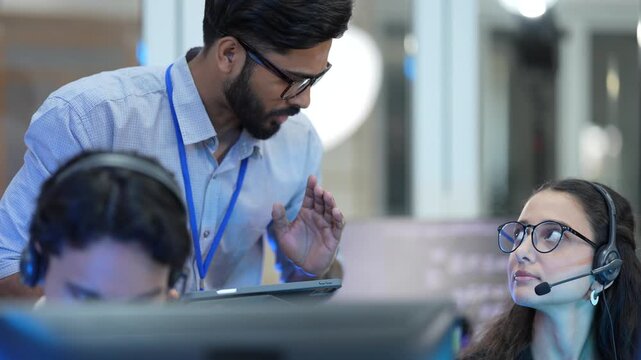 A contact center manager provides on-the-job coaching to a new CSR, explaining a complex customer ticket and reviewing the call script to improve her performance metrics.