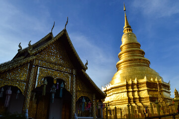 Naklejka premium Church and Golden pagoda in evening, Lanna Architecture, Symbols of Buddhism, South East Asia at wat phra that hariphunchai in Lamphun, north, Thailand
