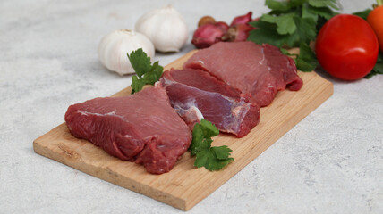 fresh raw meat on a cutting board with soup vegetables on the side	
