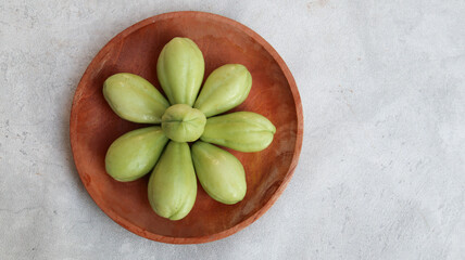 Baby chayote (labu siam) on wooden plate with grey background	
