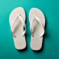 Pair of white flip flops with decorative straps on a teal background
