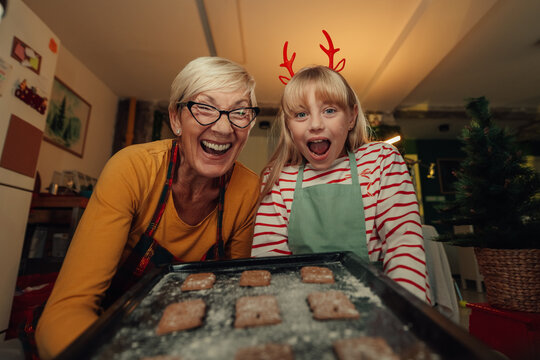 Grandmother and granddaughter showing christmas cookies baking pan