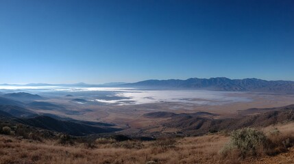 High desert valley shrouded in fog beneath a clear, blue sky