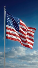 An American flag waves proudly on a flagpole against a blue sky dotted with fluffy white clouds, symbolizing patriotism and freedom
