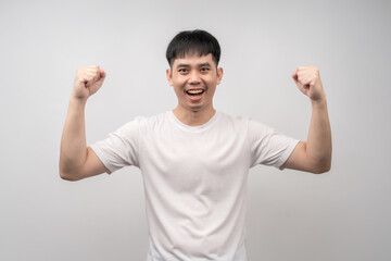 A handsome young man smiles happily and raises his fist in a triumphant gesture. Ideal for concepts in business, finance, technology, and advertising, or for showcasing products and ideas.