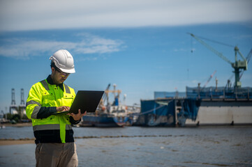 A coast guard is inspecting the shoreline used for mooring large cargo ships through a laptop