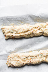overhead view of savory biscotti dough on a parchment lined baking sheet, top view of savory cookie dough on parchment paper