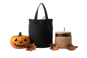 Halloween decor featuring a pumpkin, a black tote bag, and a rustic container surrounded by autumn leaves.