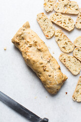 overhead view of slicing savory biscotti, top view of thinly slicing bread for making bread chips, top view of making crostini bread slices