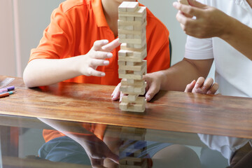Asian father and son playing wood blocks game Carefree kid playing wood blocks game building constructor from blocks with father at home