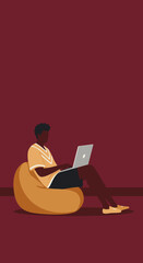 Young man comfortably working or studying on a laptop from a bean bag chair. Represents remote work, online learning, or casual digital lifestyle.