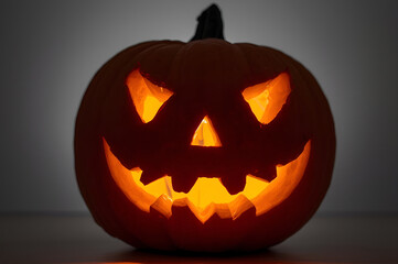 Halloween jack o lantern pumpkin with scary face carving lit up on black background