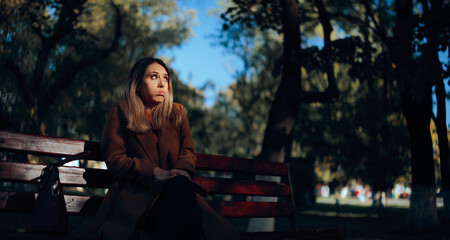 Anxious Woman Waiting on a Bench in the Park. Girlfriend awaits for her date feeling emotional and...