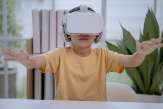 Asian girl wearing VR headset and raising hands, experiencing virtual reality. Concept of child using immersive technology, digital learning, gaming, creativity and future innovation.