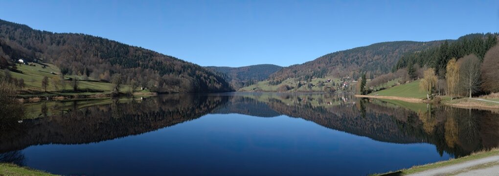Serene lake reflecting hills under a clear sky