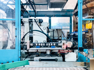 Blow molding machine producing clear plastic bottles on factory production line.