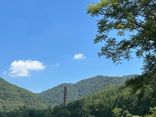 Ancient Tower Rising from Verdant Valley under Blue Sky