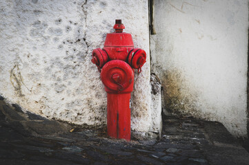 Old fire hydrant on a street in Portugal in front of an old deteriorated white façade – Bragança