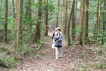 Obraz premium A woman is walking through a forest with a baby in her arms. Scene is peaceful and serene, as the woman and baby enjoy their time in nature