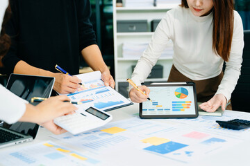 Business documents on office table with smart phone and laptop and three colleagues discussing data...