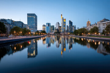 Obraz premium City skyline reflected in calm river at dusk