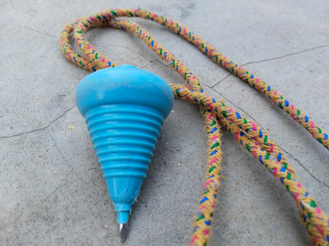Traditional Indian lattu spinning top with attached string placed on dusty ground, representing desi childhood games, rural playtime preparation, and nostalgic moments of classic toys