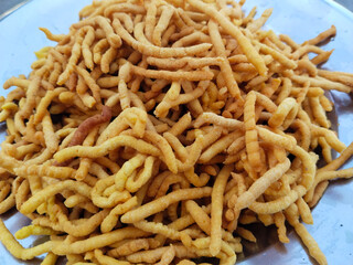 Freshly prepared crispy ajwain besan sev served in a traditional plate, deep-fried Indian snack made with gram flour, salt and carom seeds, home-cooked namkeen food photography