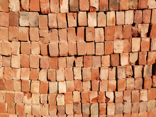 High stack of red bricks arranged in layered pile for construction site storage, traditional Indian building materials in organized bricklaying pattern