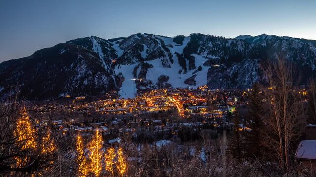 Timelapse of Aspen Colorado luxury ski resort at night with illuminated town and snowy mountains, winter travel destination in the Rocky Mountains USA, famous ski slopes, holiday lights and alpine sce