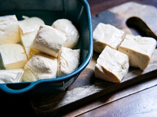 Fresh raw tofu in a plastic basket and on a cutting board. Fresh tofu ready to cook.