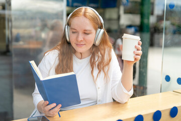 Young woman enjoys a quiet moment reading a book and sipping coffee in a modern cafe during daylight hours
