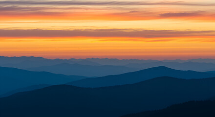 Fototapeta premium Majestic mountain range silhouetted against a vibrant sunset sky at dusk