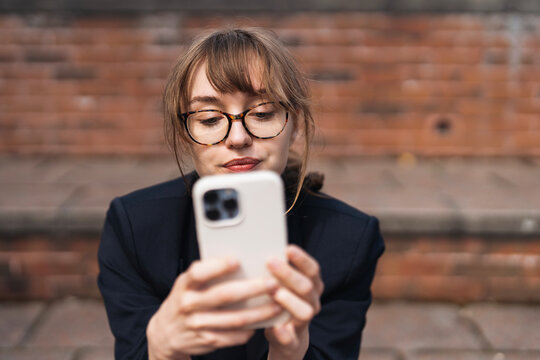 Young woman using smartphone while sitting on steps in an urban setting during daytime