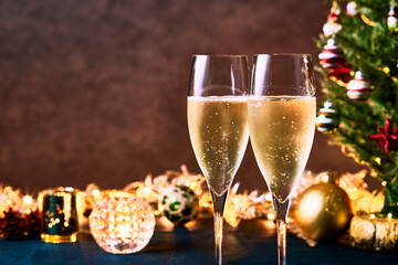 クリスマスツリーとイルミネーションを背景に並んだシャンパングラス　二人の乾杯やお祝いをイメージさせる華やかなシーン　冬のパーティーやホリデーシーズンにぴったりの雰囲気