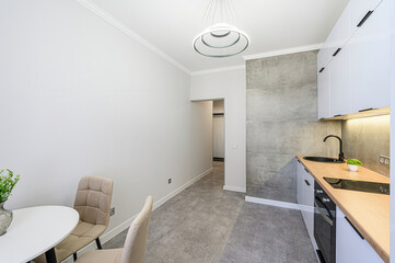 Modern kitchen and dining area with a round table, two chairs, and sleek, minimalist decor