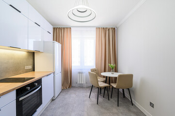 modern kitchen with white cabinets, a wooden countertop, and a round dining table with beige chairs under a unique pendant light