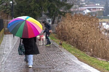 Woman walking with colorful umbrella on Lake Lugano.