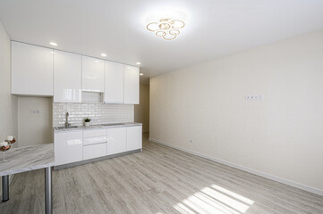 bright, modern kitchen features white cabinets, a light gray floor, and a unique ceiling light. The space is minimalist and clean