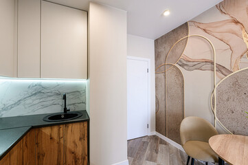 Modern interior with kitchen cabinets, marble backsplash, abstract wallpaper, and wooden floor....
