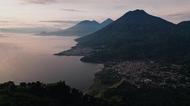 A spectacular drone shot captures a solitary figure standing on the iconic Indian's Nose viewpoint, overlooking the vast Lake Atitl&aacute;n at sunrise.