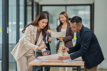 Group of Asian businesspeople sits down for a business investment planning meeting.	