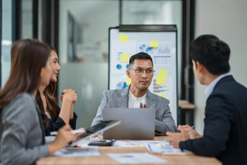 Group of Asian businesspeople sits down for a business investment planning meeting.	