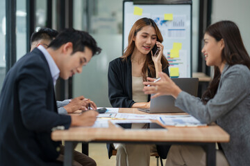 Group of Asian businesspeople sits down for a business investment planning meeting.	