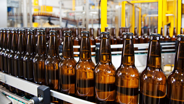 Amber glass bottles on conveyor belt brown beverage