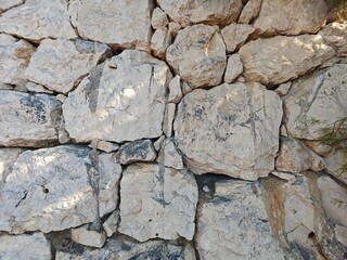 Natural stone wall with textured surfaces and unique patterns in bright sunlight