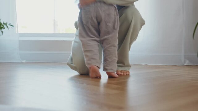 Tracking shot shows two year old boy running barefoot across a bright living room towards his mother waiting with open arms. A lively family scene of joy, growth, and emotional support. 4k footage