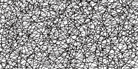 Dry earth cracks under an old gray stone wall with a chain link fence, its texture and pattern visible in the drought-ridden ground