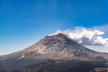 A mountain with a cloud in the sky. The mountain is covered in snow and has a grayish color. Iztacihuatl popocatepetl volcano mexico,